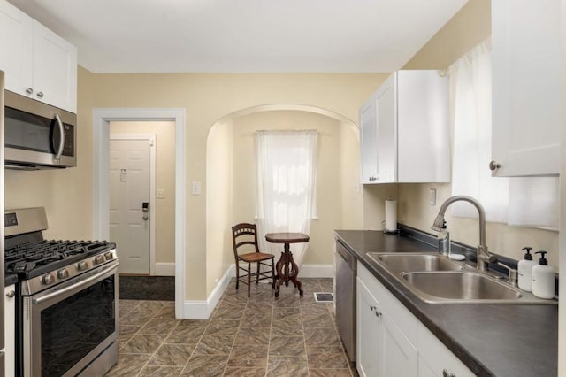 1750 Sims Ave, Saint Paul, MN 55106 - kitchen featuring appliances with stainless steel finishes, a sink, dark countertops, and white cabinets