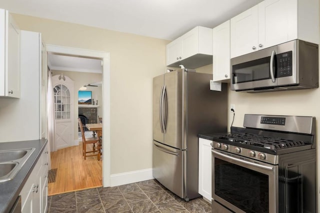 1750 Sims Ave, Saint Paul, MN 55106 - kitchen featuring stainless steel appliances, white cabinets, a sink, dark countertops, and baseboards