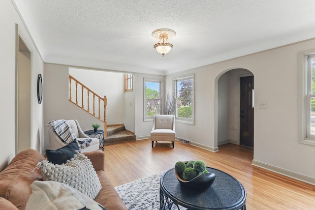 218 Owens St N, Stillwater, MN 55082 - living room featuring arched walkways, plenty of natural light, light wood-style floors, stairs, and a textured ceiling
