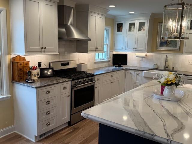 331 Willamor Cir, Albert Lea, MN 56007 - kitchen featuring stainless steel gas range, wall chimney exhaust hood, light wood-style floors, white cabinets, and recessed lighting