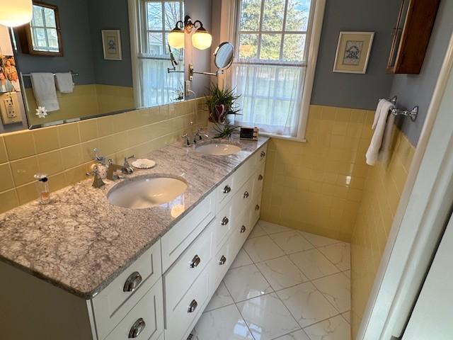 331 Willamor Cir, Albert Lea, MN 56007 - bathroom featuring healthy amount of natural light, double vanity, tile walls, and a wainscoted wall