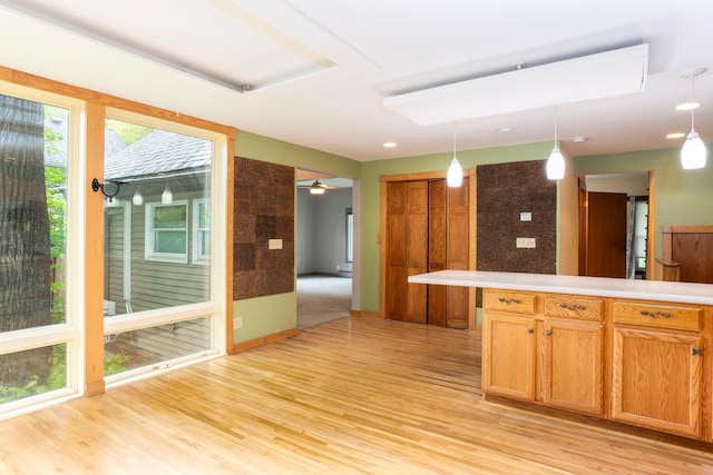 428 4th St, River Falls, WI 54022 - kitchen featuring light wood-type flooring, hanging light fixtures, light countertops, and brown cabinetry