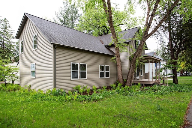 428 4th St, River Falls, WI 54022 - view of side of property with a shingled roof, a wooden deck, and a lawn