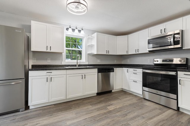806 4th St, Marshall, MN 56258 - kitchen featuring stainless steel appliances, a sink, open shelves, white cabinetry, and light wood-style flooring