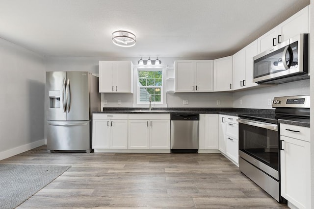 806 4th St, Marshall, MN 56258 - kitchen featuring appliances with stainless steel finishes, a sink, white cabinets, and light wood finished floors