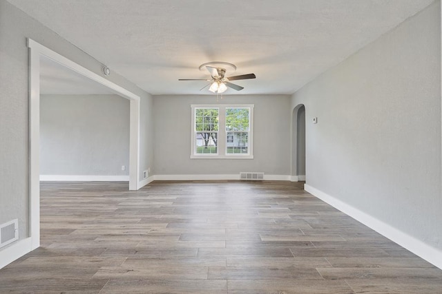 806 4th St, Marshall, MN 56258 - empty room featuring ceiling fan, arched walkways, wood finished floors, and baseboards