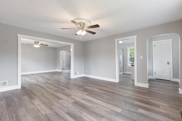 806 4th St, Marshall, MN 56258 - empty room featuring ceiling fan, baseboards, wood finished floors, and arched walkways