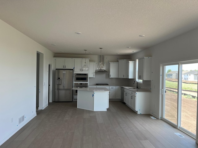 2719 Aspen Dr, Shakopee, MN 55379 - kitchen featuring appliances with stainless steel finishes, wall chimney exhaust hood, a sink, a center island, and baseboards