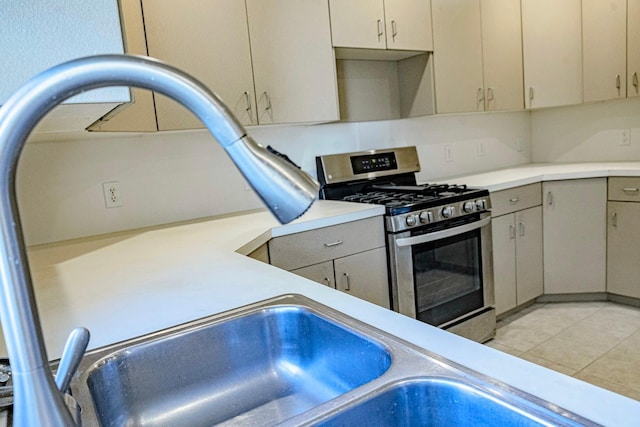 101 6th St NW, Perham, MN 56573 - kitchen featuring stainless steel range with gas stovetop, light countertops, gray cabinets, and light tile patterned floors