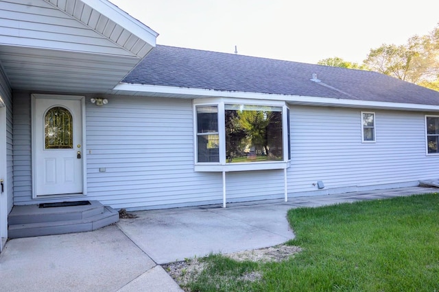 101 6th St NW, Perham, MN 56573 - entrance to property featuring a shingled roof, a patio area, and a yard