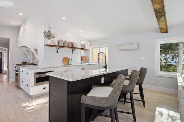 168 1st St, Excelsior, MN 55331 - kitchen with a sink, a wall mounted AC, stainless steel appliances, white cabinets, and light wood finished floors