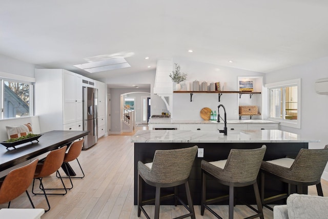 168 1st St, Excelsior, MN 55331 - kitchen with lofted ceiling, stainless steel fridge with ice dispenser, white cabinets, a center island with sink, and healthy amount of natural light