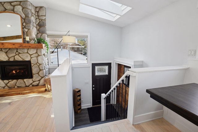 168 1st St, Excelsior, MN 55331 - staircase featuring a skylight, hardwood / wood-style floors, a stone fireplace, and lofted ceiling