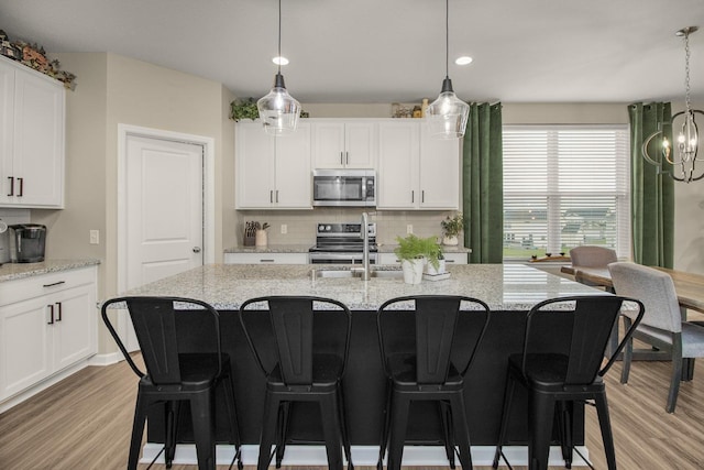 20555 Greenwood Ave, Lakeville, MN 55044 - kitchen featuring stainless steel appliances, light wood finished floors, backsplash, white cabinetry, and a kitchen breakfast bar