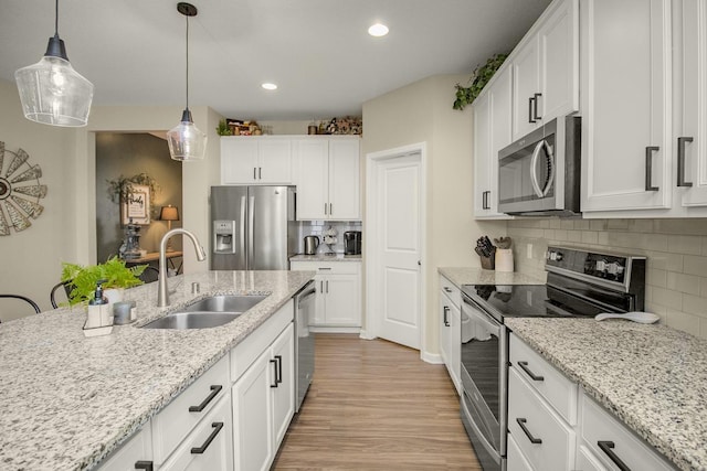20555 Greenwood Ave, Lakeville, MN 55044 - kitchen featuring appliances with stainless steel finishes, a sink, white cabinets, tasteful backsplash, and decorative light fixtures