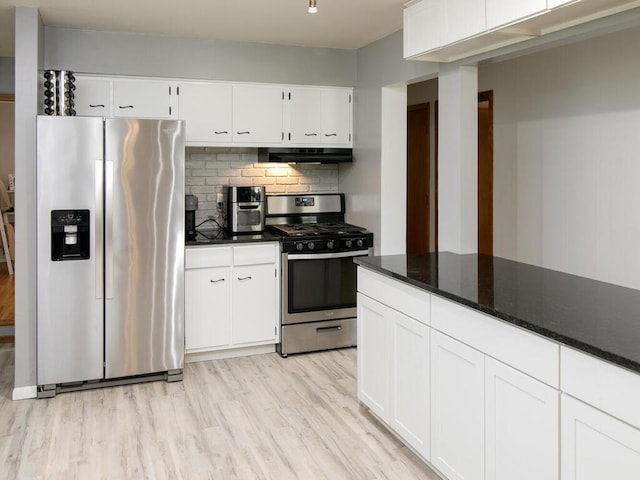 kitchen with appliances with stainless steel finishes, exhaust hood, dark countertops, and white cabinets