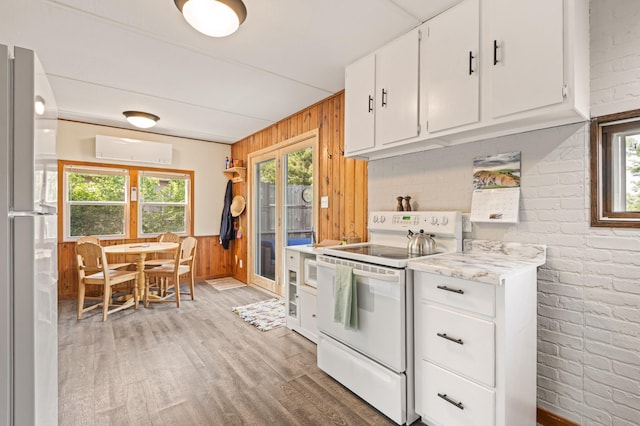 1605 White Ash Ln, Apple River Twp, WI 54810 - kitchen with white appliances, wood walls, light wood-style flooring, brick wall, and white cabinetry
