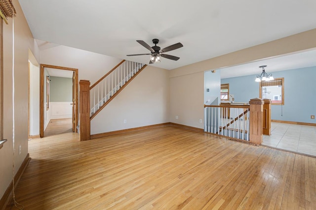 1207 Cedar Ave, Owatonna, MN 55060 - spare room featuring light wood-style floors, ceiling fan, a chandelier, and baseboards