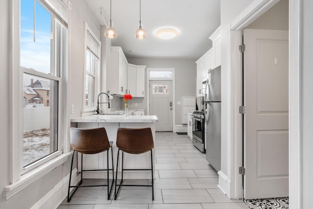 2744 Stevens Ave, Minneapolis, MN 55408 - kitchen with a sink, a peninsula, white cabinetry, a breakfast bar, and appliances with stainless steel finishes