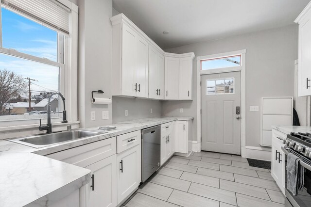 2744 Stevens Ave, Minneapolis, MN 55408 - kitchen with stainless steel appliances, a sink, white cabinets, and baseboards