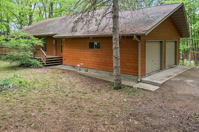 568 26th Ave, Cumberland, WI 54829 - view of side of home with a detached garage, a wooden deck, and a shingled roof