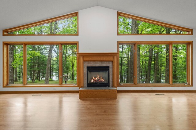568 26th Ave, Cumberland, WI 54829 - unfurnished living room with wood finished floors, vaulted ceiling, a fireplace, and plenty of natural light