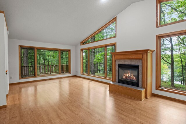 568 26th Ave, Cumberland, WI 54829 - unfurnished living room with high vaulted ceiling, a tiled fireplace, baseboards, plenty of natural light, and light wood-style floors