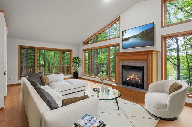 568 26th Ave, Cumberland, WI 54829 - living area featuring high vaulted ceiling, a tile fireplace, wood finished floors, healthy amount of natural light, and baseboards