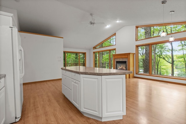 568 26th Ave, Cumberland, WI 54829 - kitchen featuring freestanding refrigerator, ceiling fan, light wood-style floors, a fireplace, and high vaulted ceiling