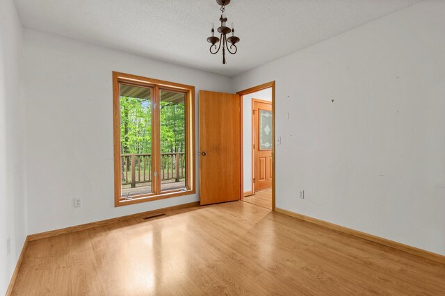 568 26th Ave, Cumberland, WI 54829 - unfurnished room featuring light wood-style flooring, a chandelier, baseboards, and a textured ceiling