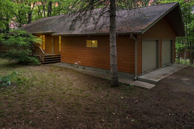 568 26th Ave, Cumberland, WI 54829 - view of side of home featuring a garage, roof with shingles, and a wooden deck