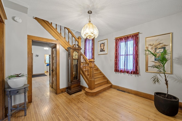 658 Plum St, Saint Paul, MN 55106 - stairs featuring a chandelier, baseboards, hardwood / wood-style flooring, and a textured ceiling