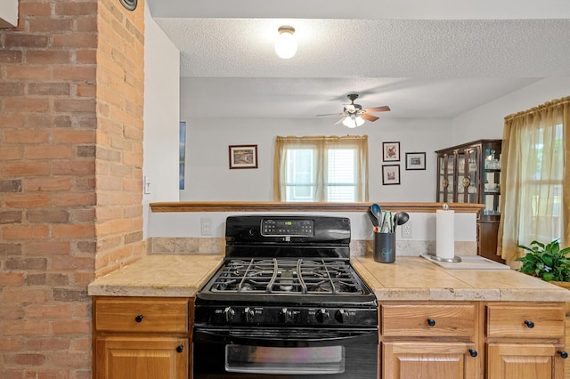 658 Plum St, Saint Paul, MN 55106 - kitchen with black gas range oven, a ceiling fan, brick wall, and a textured ceiling