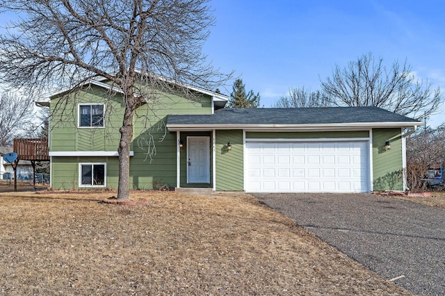 tri-level home with driveway, an attached garage, and a shingled roof