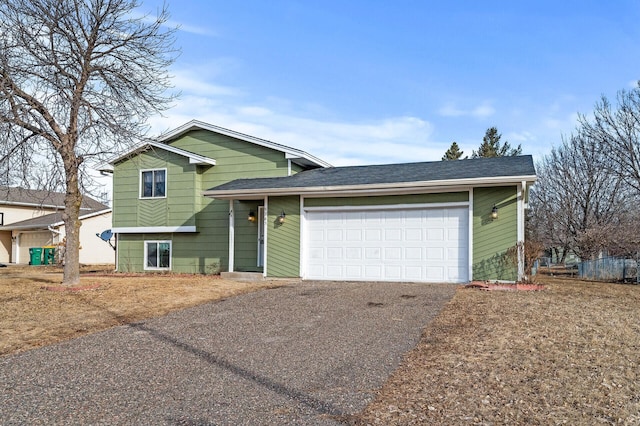 tri-level home featuring driveway, a garage, and roof with shingles