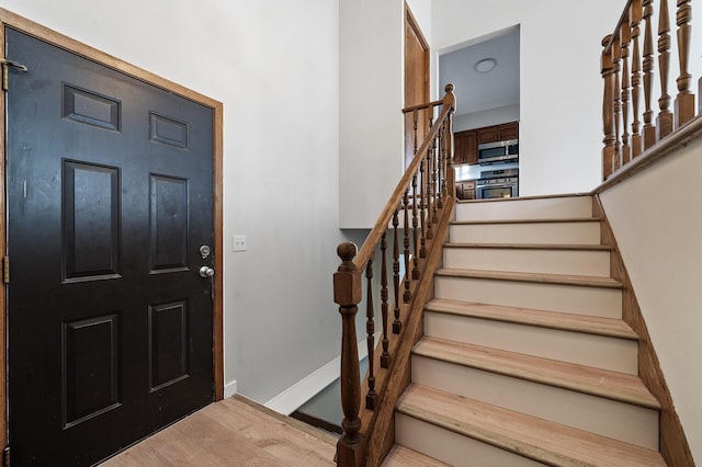 foyer entrance with stairs, wood finished floors, and baseboards