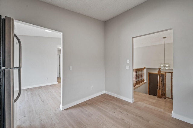 unfurnished room with wood finished floors, baseboards, and a chandelier