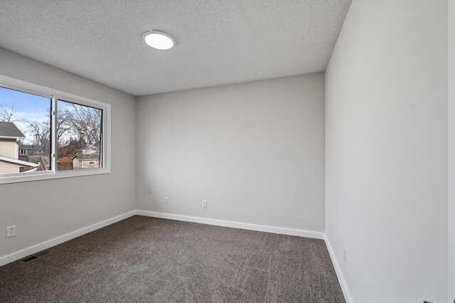 unfurnished room with dark carpet, a textured ceiling, and baseboards