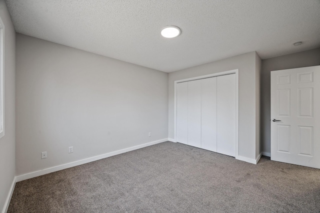 unfurnished bedroom featuring carpet, a textured ceiling, a closet, and baseboards