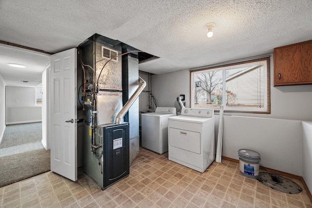 laundry area with independent washer and dryer, a textured ceiling, baseboards, light flooring, and heating unit