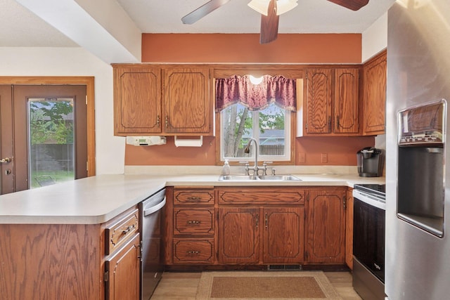 10194 Jewell St NE, Blaine, MN 55014 - kitchen featuring stainless steel appliances, a sink, light countertops, a peninsula, and brown cabinets