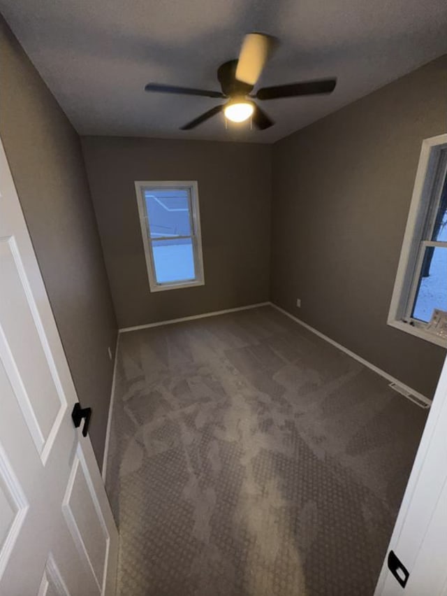 unfurnished room featuring ceiling fan, carpet, plenty of natural light, and baseboards