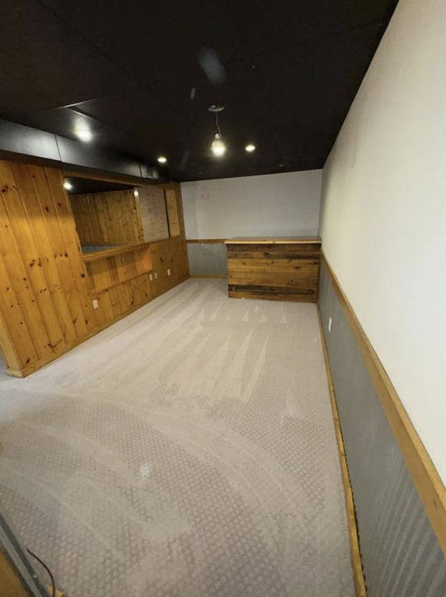 finished below grade area with wooden walls, carpet floors, and a wainscoted wall