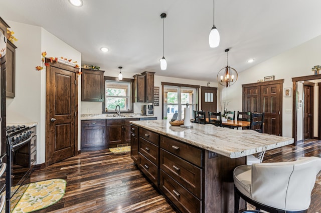 10798 Quiner Ave NW, Southside Twp, MN 55382 - kitchen with black gas range oven, dark wood finished floors, a kitchen breakfast bar, dark brown cabinetry, and vaulted ceiling