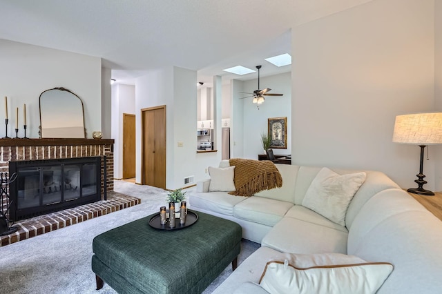 carpeted living room featuring a skylight, a brick fireplace, and ceiling fan