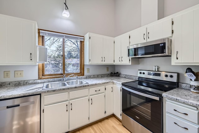 kitchen with stainless steel appliances, a sink, light countertops, and white cabinetry