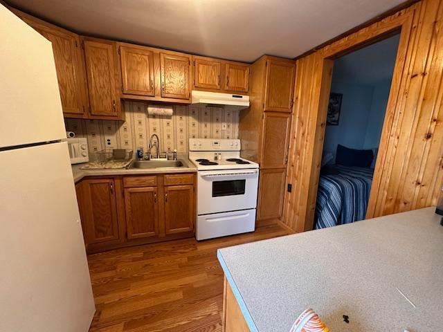 2377 Finn Bay Rd, Babbitt, MN 55706 - kitchen with white appliances, a sink, under cabinet range hood, light wood-type flooring, and brown cabinetry