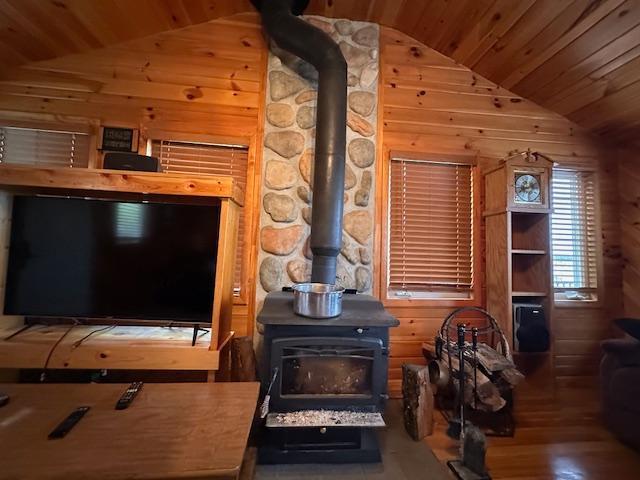 2377 Finn Bay Rd, Babbitt, MN 55706 - living area with lofted ceiling, a wood stove, wooden ceiling, wooden walls, and wood finished floors