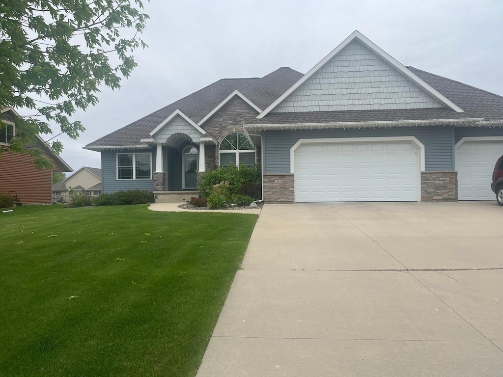 1808 4th St NE, Willmar, MN 56201 - craftsman inspired home with an attached garage, stone siding, concrete driveway, a front yard, and a shingled roof