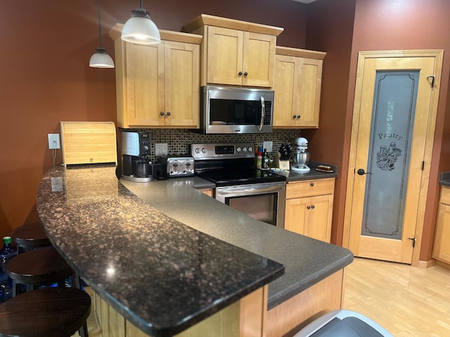 1808 4th St NE, Willmar, MN 56201 - kitchen with stainless steel appliances, dark countertops, a peninsula, tasteful backsplash, and light brown cabinetry